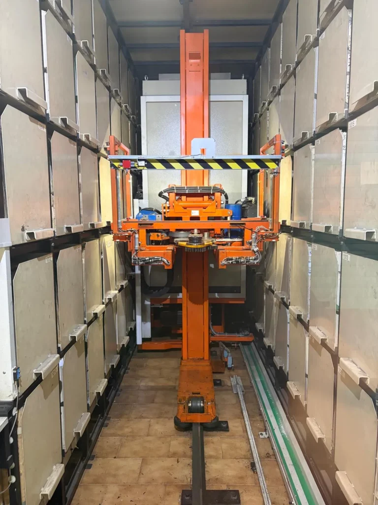 cospro, Soluzioni per Magazzini Automatici: Carro traslatore arancione in un magazzino automatico verticale, ottimizzazione spazi.